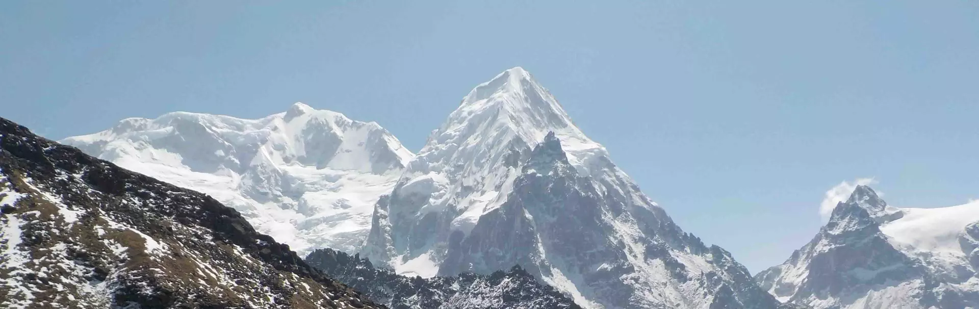 Een bergbeklimmer in een rode jas en met een skibril houdt een vlag met rode, witte en blauwe strepen vast terwijl hij op een besneeuwde bergtop staat.